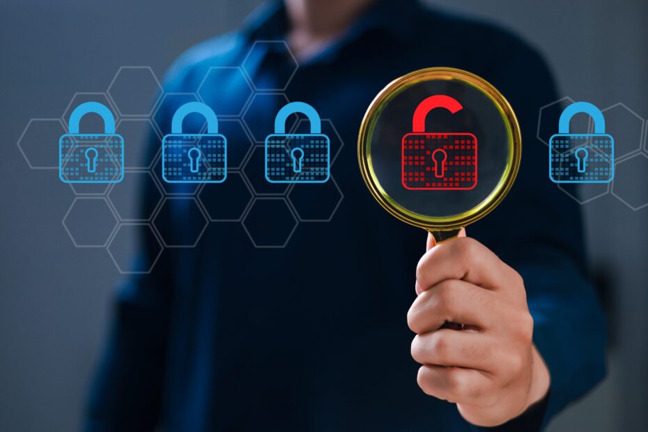 Main tenant une loupe sur un cadenas rouge déverrouillé, symbolisant l’identification d’une vulnérabilité au sein d’un système sécurisé représenté par plusieurs cadenas bleus