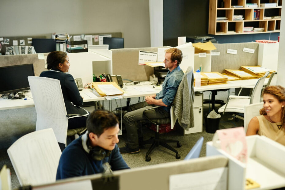 Réunion entre collègues dans un bureau open space abordant la gestion des risques numériques et la pertinence de mettre en place une solution d'ASM cyber