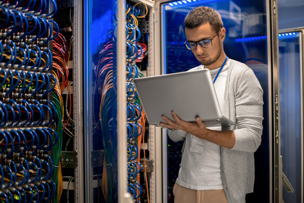 Technicien en cybersécurité vérifiant l’état du réseau dans une baie de serveurs pendant un audit réseau