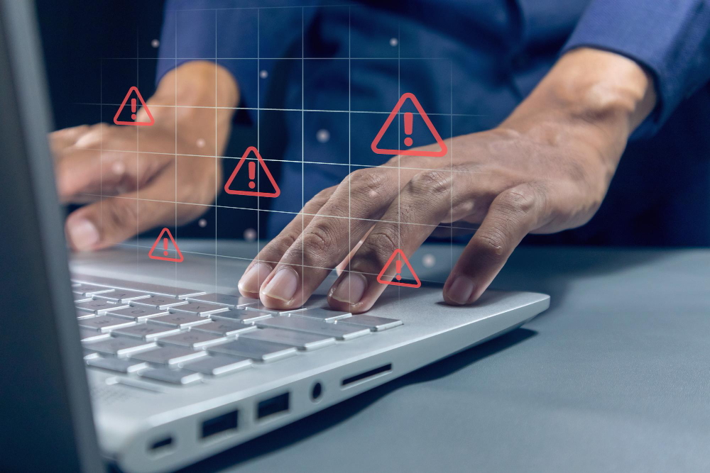Homme travaillant sur un ordinateur portable avec un signe d'avertissement de triangle rouge sur l'écran pour des fuites de données